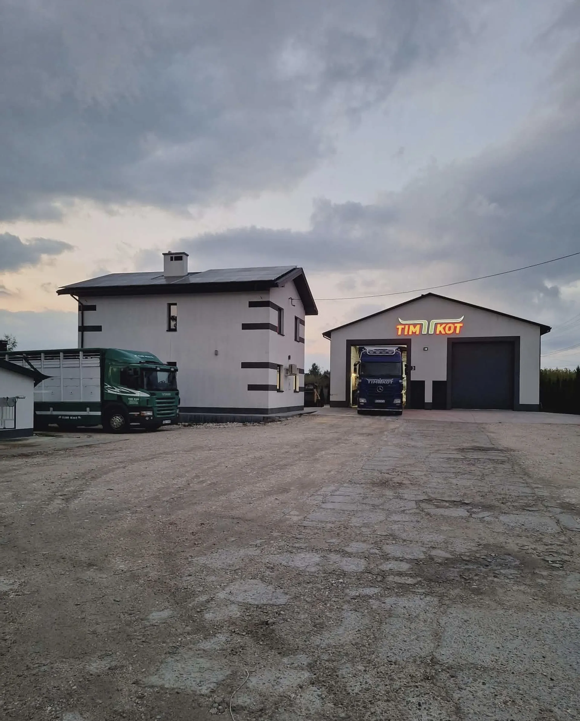 Ciężarówki z przyczepami do przewozu zwierząt zaparkowane przy firmowym budynku Transport zwierząt